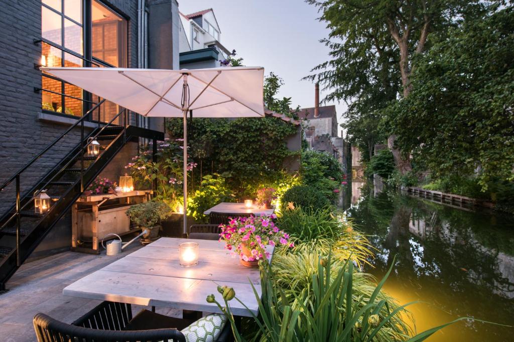 a patio table with umbrellas on the water at B&B Huis Koning in Bruges