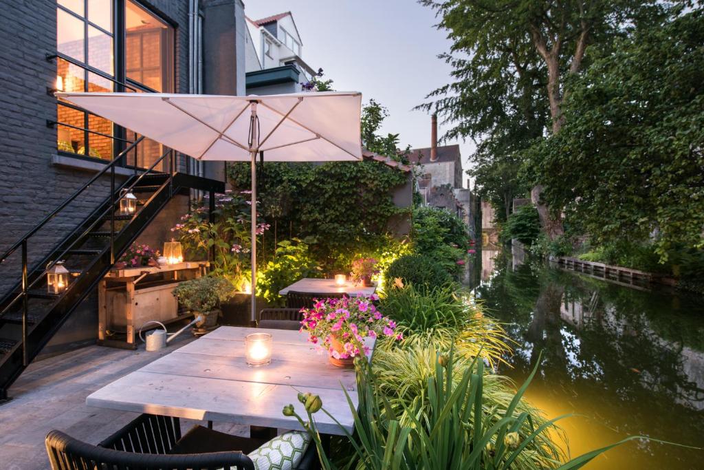 a table with an umbrella on a patio next to a river at B&B Huis Koning in Bruges