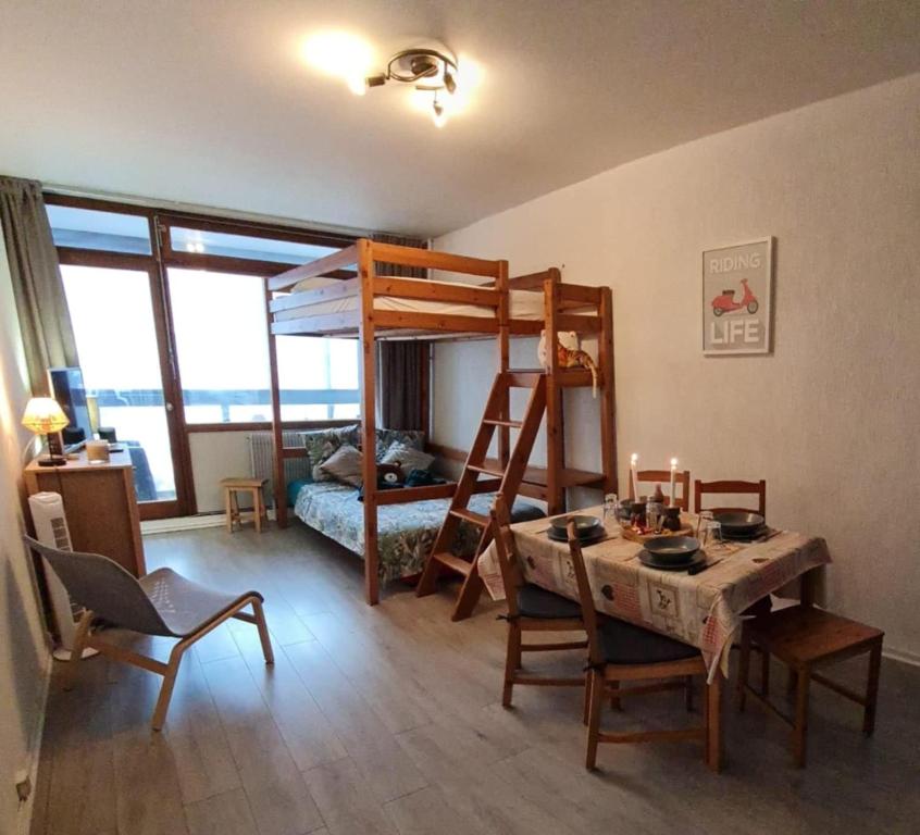 a room with a dining table and a bunk bed at La marmotte in La Bresse