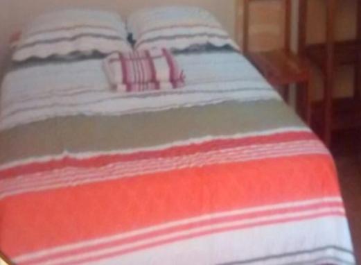 - un lit avec des draps et des oreillers rouges et blancs à rayures dans l'établissement Rosa1, à Pucalá