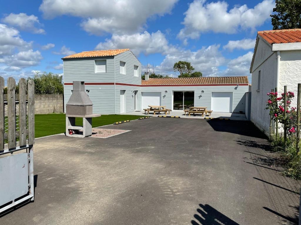 un garage avec un bâtiment blanc et une clôture dans l'établissement Maison 1 chambre 2 personnes, à Talmont-Saint-Hilaire