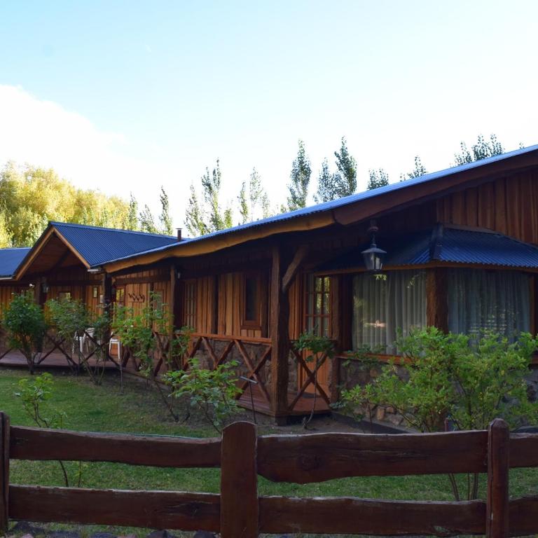 a wooden cabin with a fence in front of it at Chacra Kaiken Lodge in Perito Moreno
