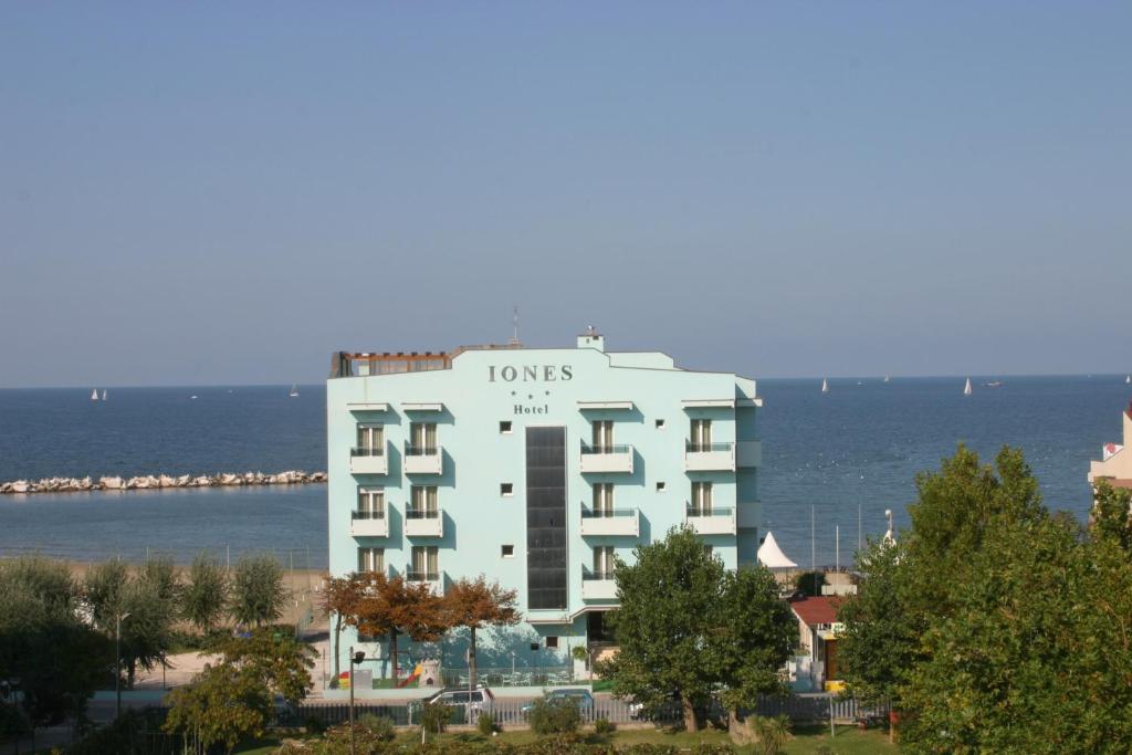 ein großes weißes Gebäude mit dem Ozean im Hintergrund in der Unterkunft Hotel Iones in Rimini