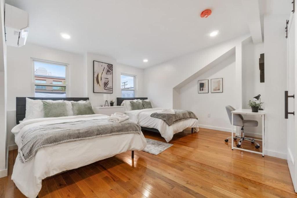 two beds in a bedroom with white walls and wood floors at 3 BDRM 2 and a Half Bath - House Private Yard Duplex in Pittsburgh