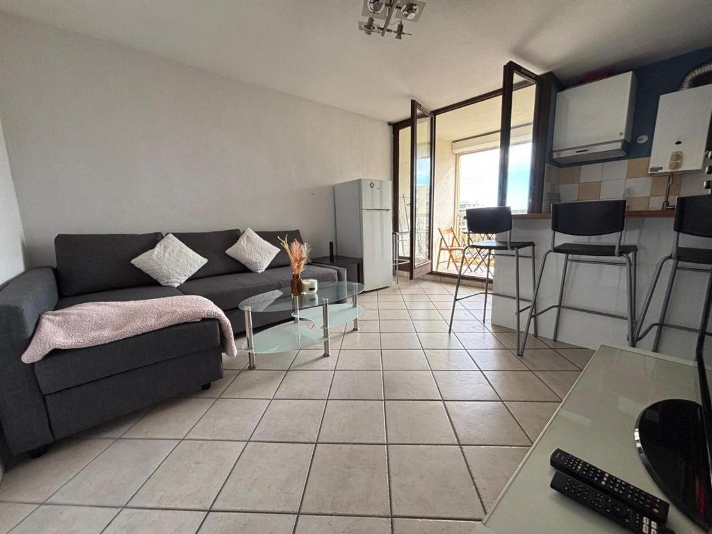 un salon avec un canapé et une cuisine dans l'établissement Carnon-Plage Appartement lumineux proche plage, à Mauguio