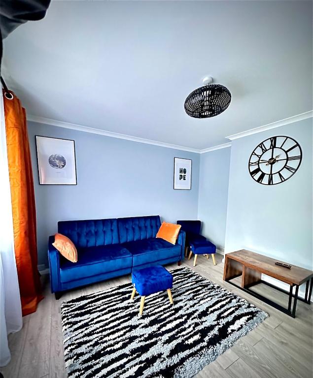 a living room with a blue couch and a table at Cozy 2-Bed Detached Bungalow with Parking Woking in Horsell