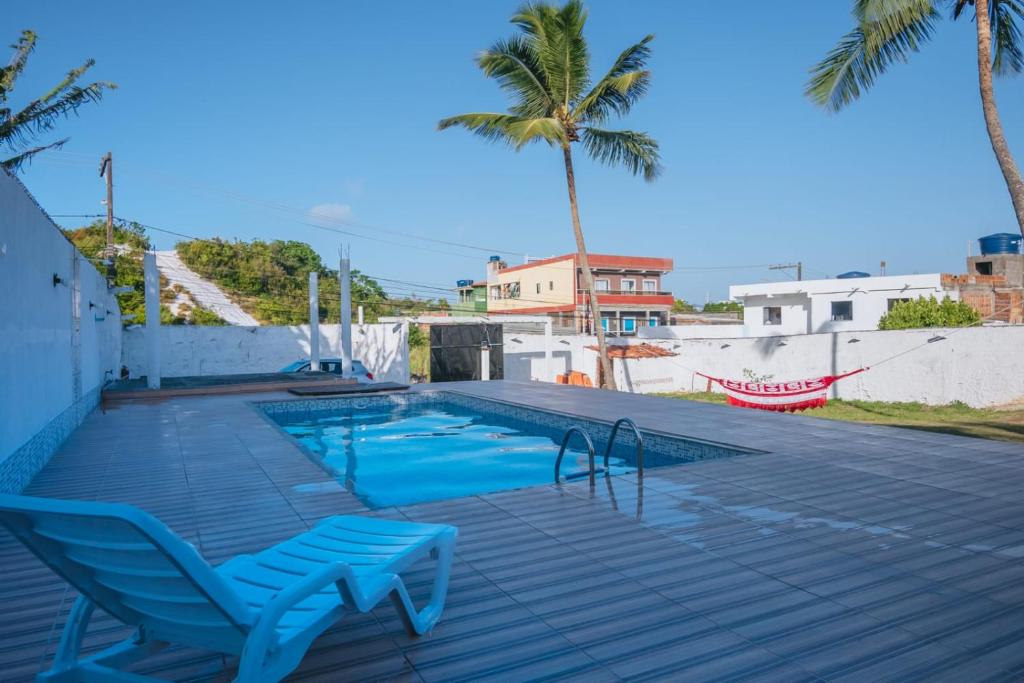 a swimming pool with a blue chair and palm trees at Villa Jauá, praia, piscina e vista para duna in Camaçari