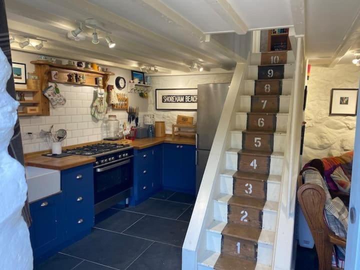 a kitchen with blue cabinets and a spiral staircase at Little Cottage, Llwyngwril in Llwyngwril