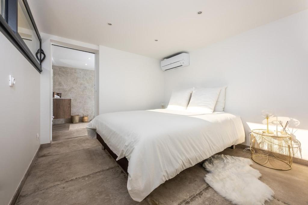 une chambre blanche avec un grand lit et une table dans l'établissement Appartement au pied des Calanques de Cassis, à Cassis