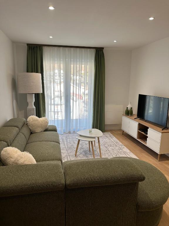 un salon avec un canapé et une télévision à écran plat dans l'établissement Villa la source, à Brides-les-Bains