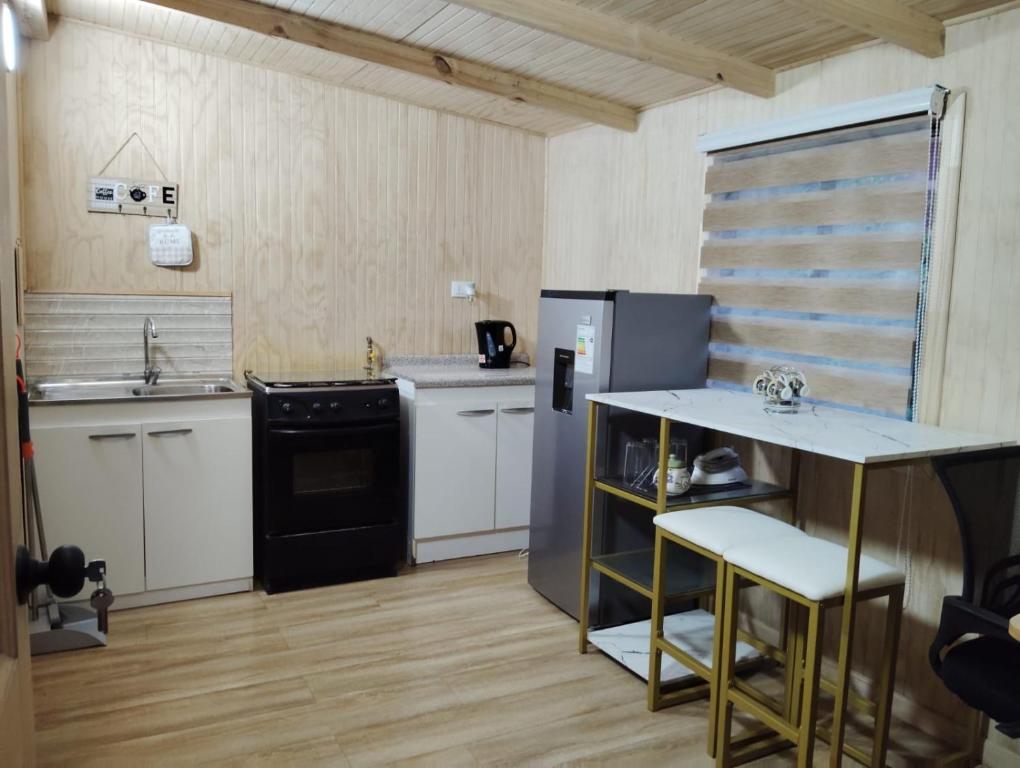 a kitchen with a refrigerator and a table and chairs at Cabaña interior en barrio residencial in Puerto Montt