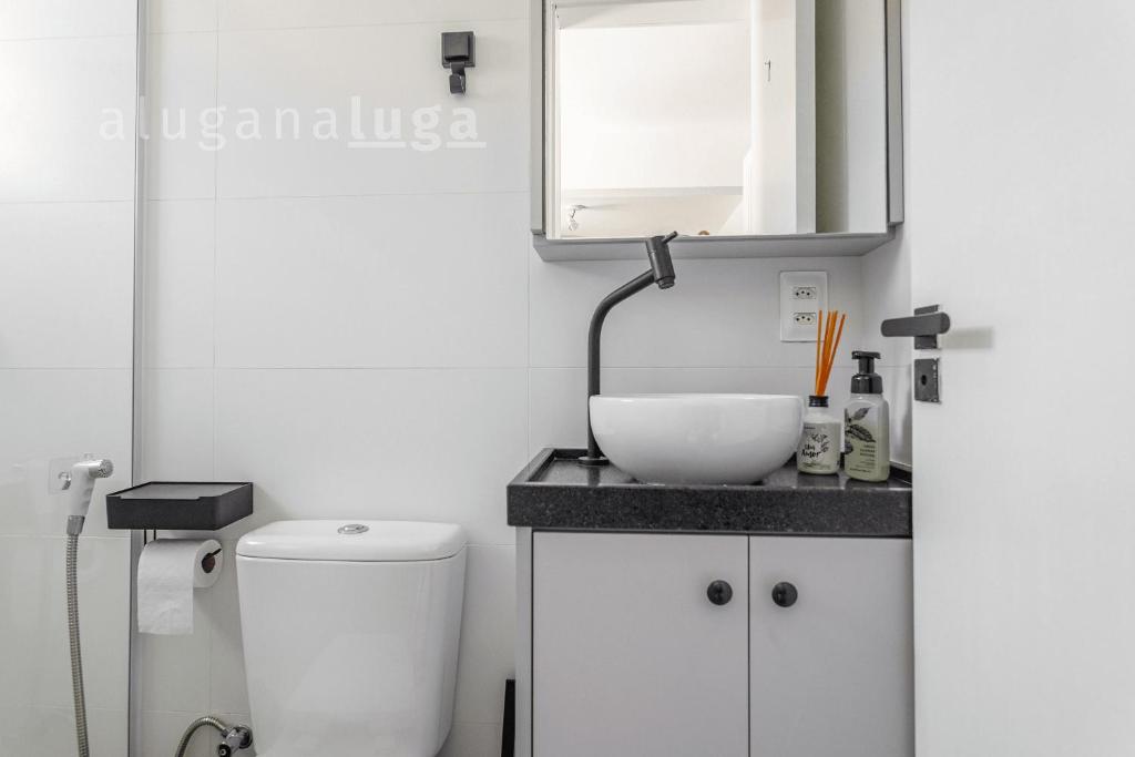 a white bathroom with a sink and a mirror at Casa pé na areia SC - Espaço completo in Guaporanga