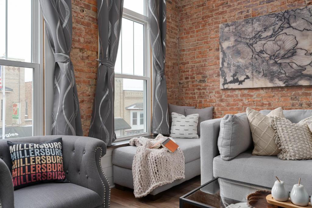 a living room with two couches and a brick wall at Chic Downtown Getaway - Fireplace & Soaking Tub - by Cross-Key Vacation Rentals in Millersburg