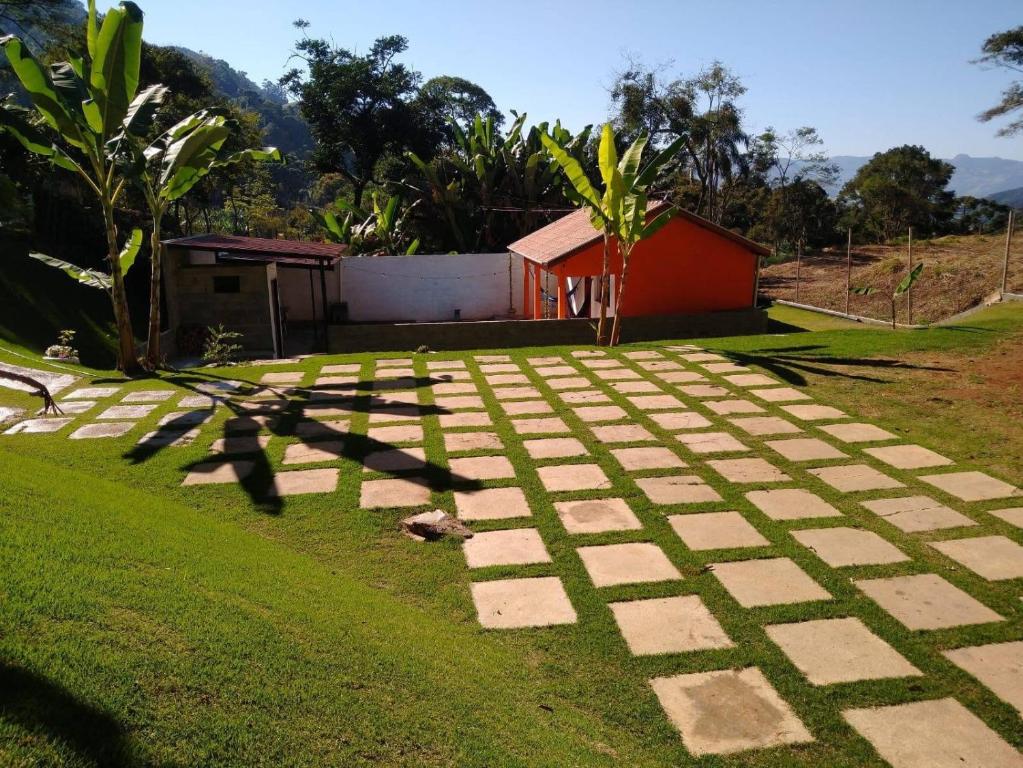 a stone pathway in a yard with a house in the background at Chalé Primavera em Gonçalves in Gonçalves