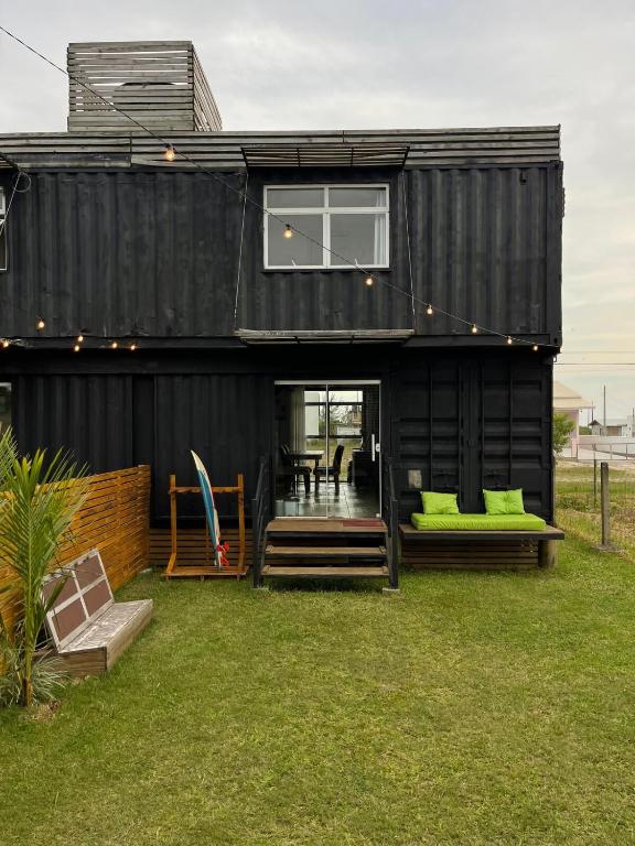 a black house with green pillows on the grass at The Box Container House casa oceano in Imbituba