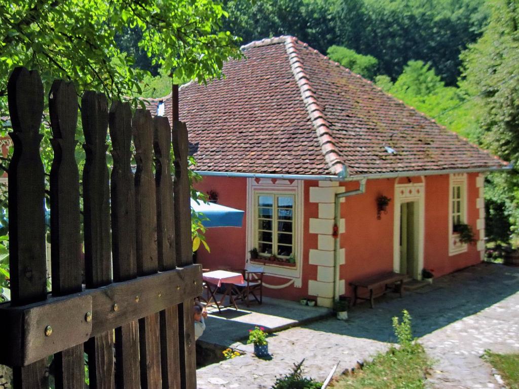 a small red and white house with a fence at Ethno Village Slatkovac in Aleksandrovac