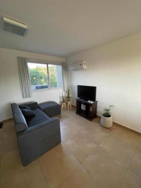 a living room with a couch and a tv at Departamento Lago Los Molinos in Villa Ciudad de America