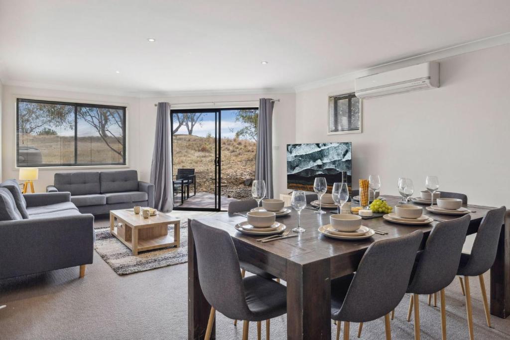 Una sala de estar con una mesa y sillas de madera. en Apres 9, en Jindabyne