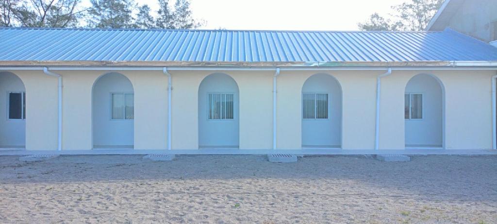 ein weißes Gebäude mit Bögen und einem blauen Dach in der Unterkunft Westward Surf Zambales Beach Resort in La Paz