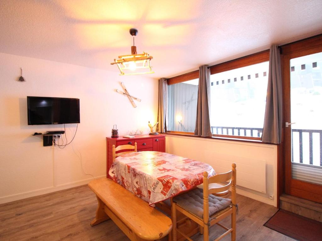 Cette chambre dispose d'une table, d'une télévision et de quelques fenêtres. dans l'établissement Appartement 2** proche pistes avec parking - 5 couchages - Mont-Dore - FR-1-415-114, à Le Mont-Dore