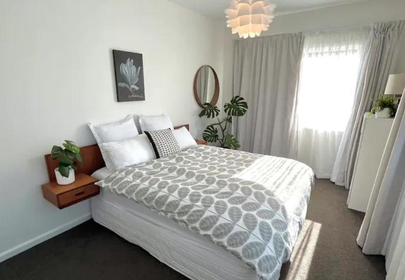 a bedroom with a large bed and a chandelier at 10 Nikau Place in Christchurch