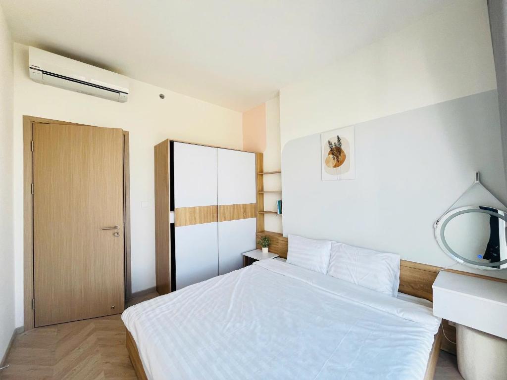 a bedroom with a white bed and a mirror at May Homes - Masterise Centre Point Vinhomes Grand Park in Long Bình