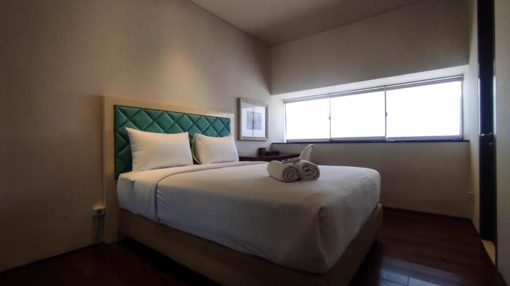a bedroom with a large white bed with a window at Apartment 3BR with River View in City Center at Sumatra36 Surabaya By Travelio in Surabaya