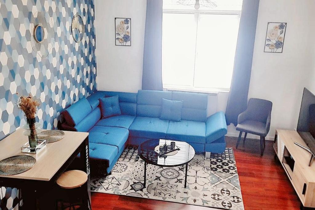 un salon avec un canapé bleu et une table dans l'établissement Appartement cocooning à Raismes - 48 m² - Idéal pour 4 personnes, à Raismes
