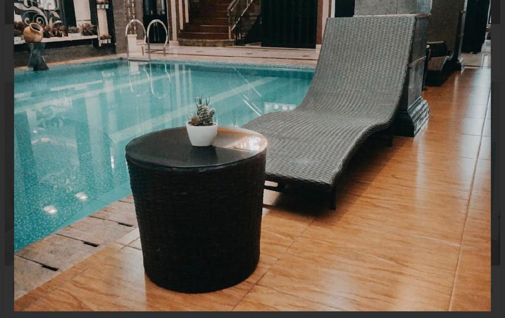 a pool with a table and a chair and a plant at Ratu Homestay in Tanjungkarang