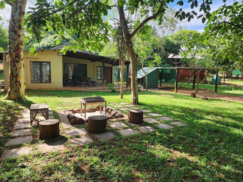 a garden with a picnic table and three logs at Mkumbi Farm Cottage in Hluhluwe