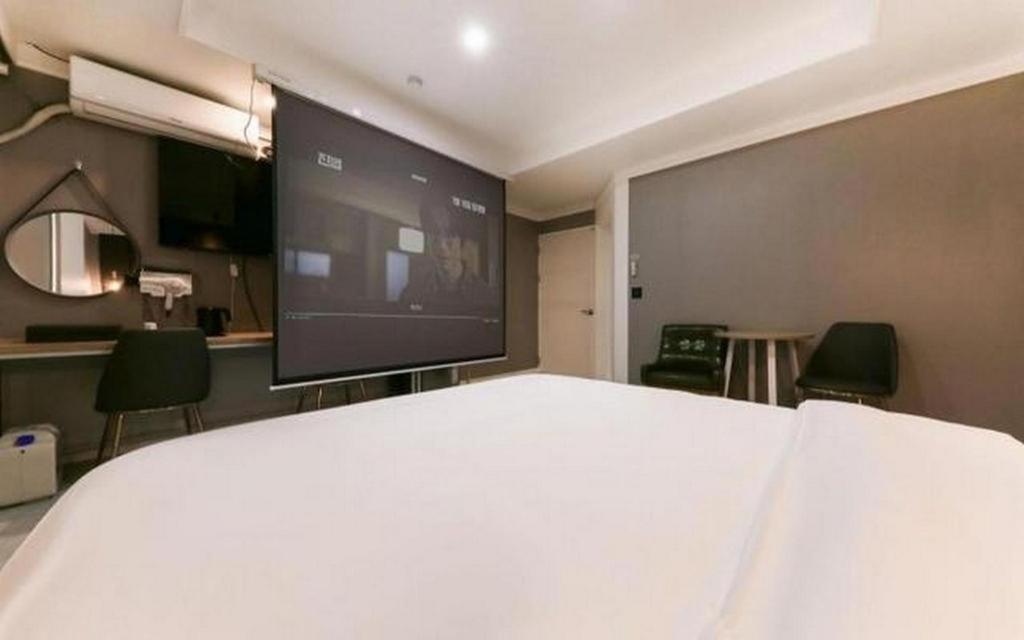 a room with a large white bed and a large screen at Best In City Hotel in Daejeon