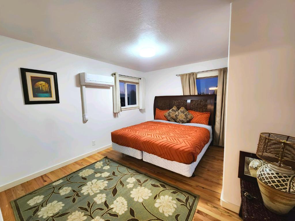 a bedroom with a bed with orange sheets and a rug at Comfortable Jacksonville house in Medford