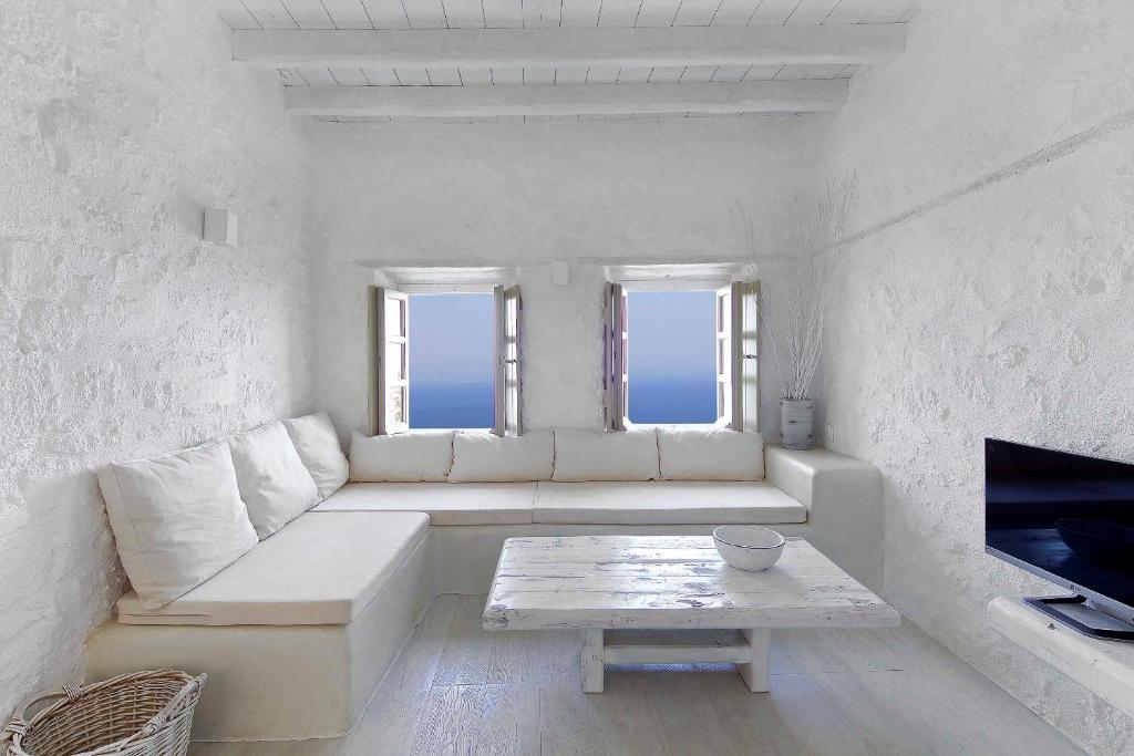 ein weißes Wohnzimmer mit einem Sofa und einem Tisch in der Unterkunft MELANOPETRA boutique apartments in Emporeiós