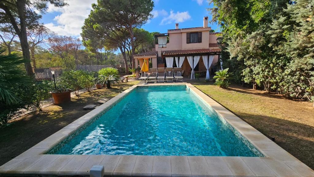 a swimming pool in front of a house at Villa Pinewood in Santa Margherita di Pula