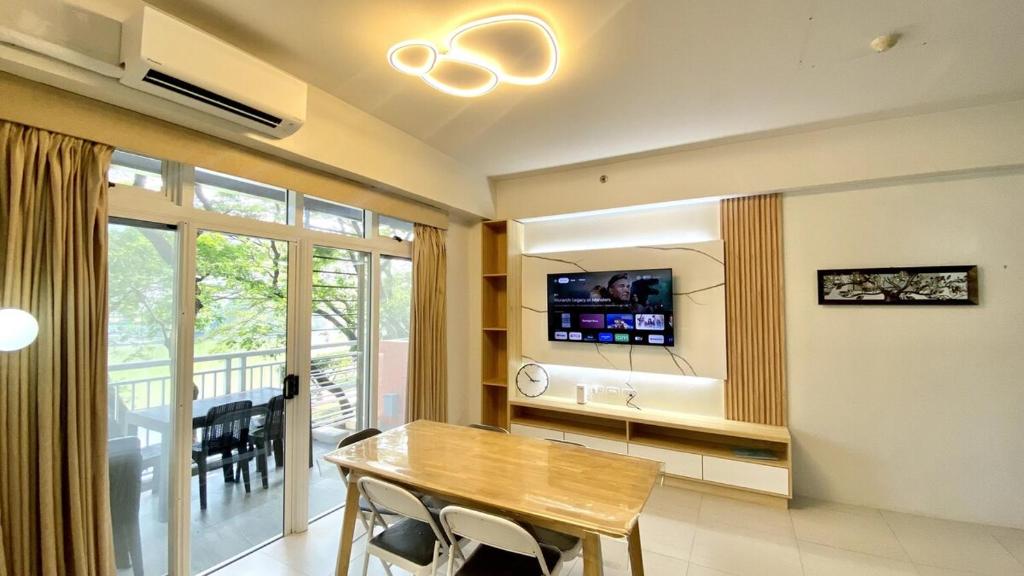 a dining room with a table and a tv on a wall at Pico de Loro 2BR Spacious Modern Zen with Lagoon View in Nasugbu
