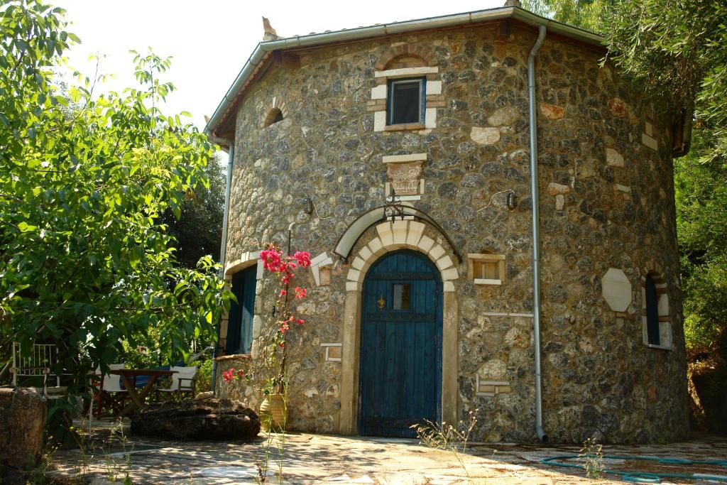 a small stone building with a blue door at Musician's Round House & Castello in Vátos