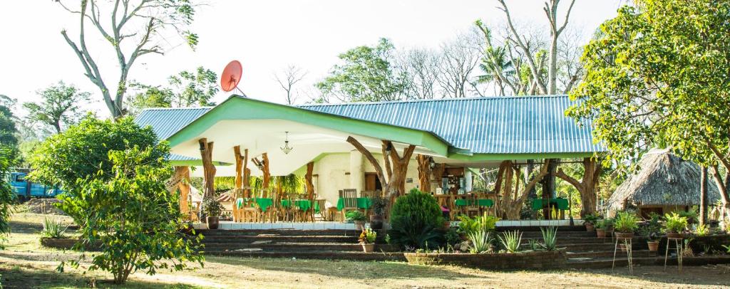 a house with a blue roof and chairs and trees at Hostal y Restaurante Rancho Merida in Mérida