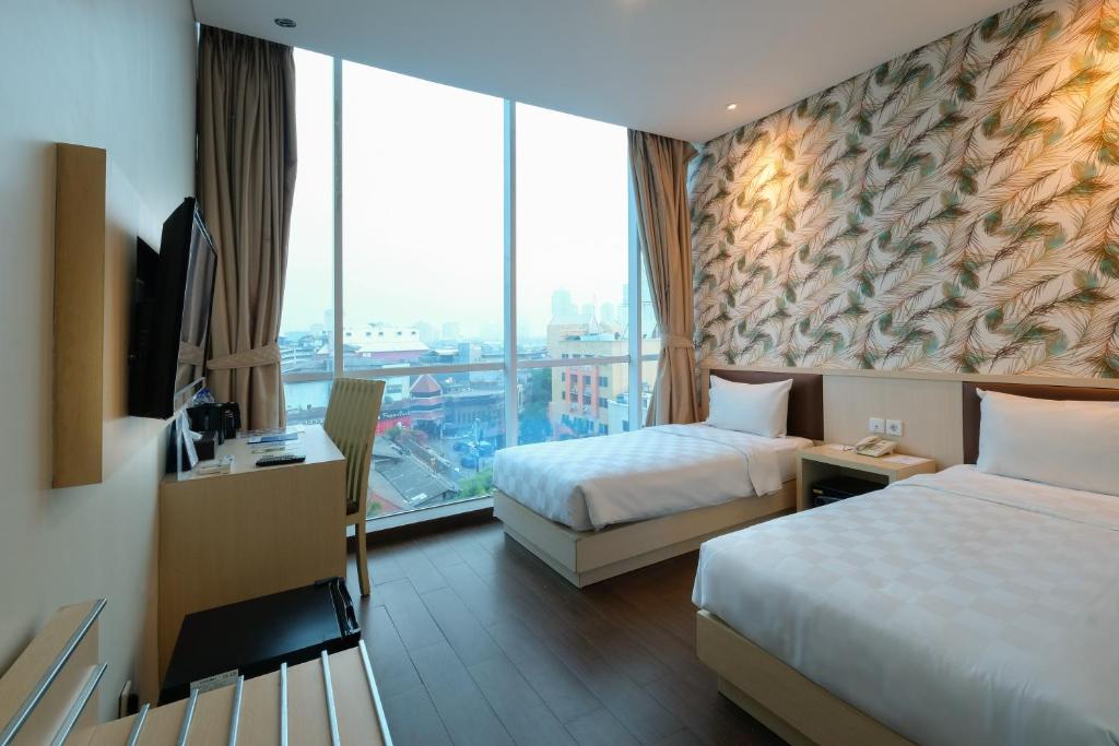 a hotel room with two beds and a large window at Hotel 88 Mangga Besar 62 - Best Breakfast - Near By Ancol And Government Center in Jakarta