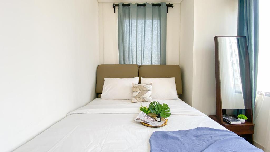 a bedroom with a white bed with a plant on it at Comfort Living 2BR at Transpark Cibubur Apartment By Travelio in Depok