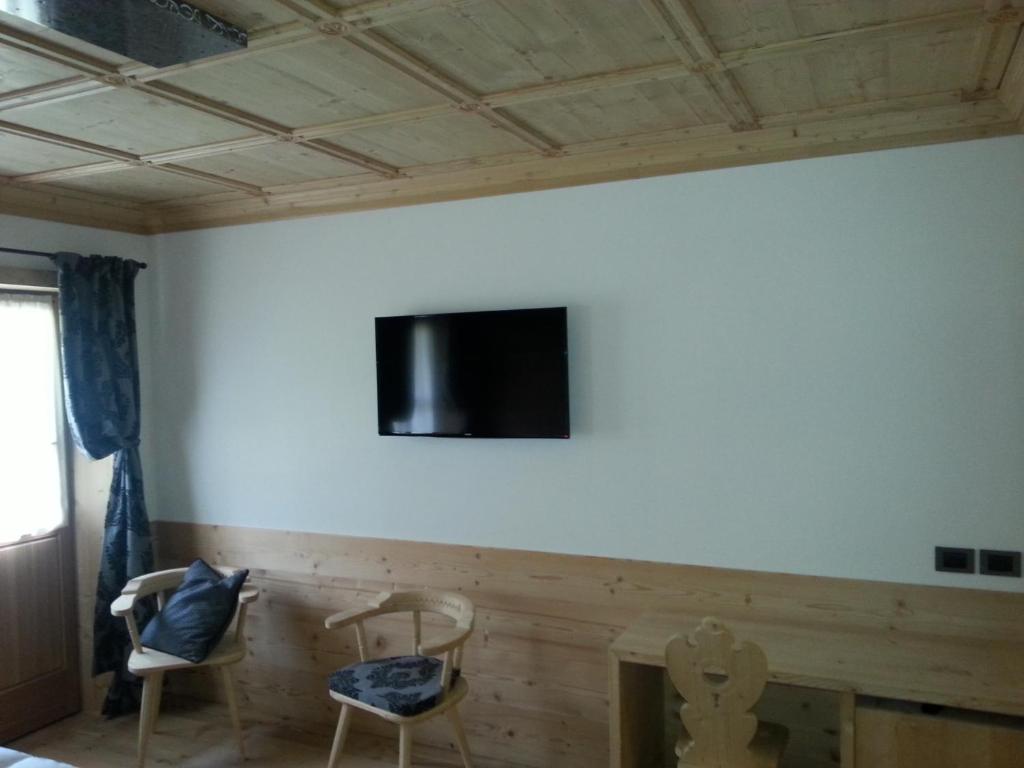 a room with two chairs and a tv on the wall at Jägerhaus Agriturismo in Cortina dʼAmpezzo