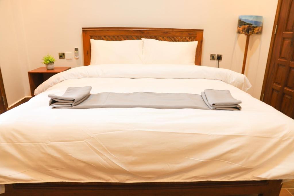 a large white bed with two pillows on it at River House Lodge International in Arusha