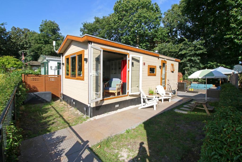 a white tiny house with a porch and a patio at KD 808 - Vakantiepark Kijkduin in The Hague