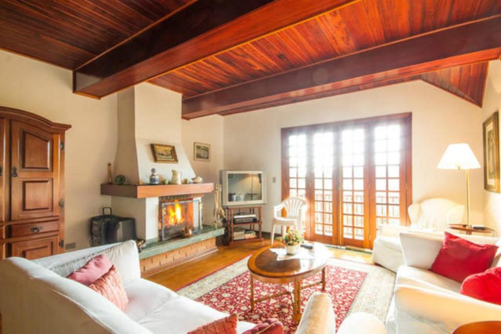 a living room with a couch and a fireplace at Apartamento Espaçoso Vista Montanha in Campos do Jordão