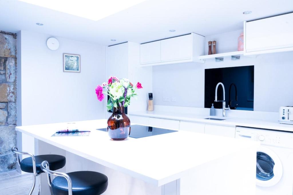 eine weiße Küche mit einer Vase aus Blumen auf der Theke in der Unterkunft Luxury modern canal side cottage for families, couples, contractors and dog friendly in Lancashire sleeps 6 in Preston