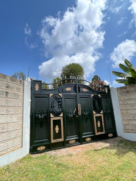 a gate in a fence with a blue sky in the background at Aberdare Home in Othaya