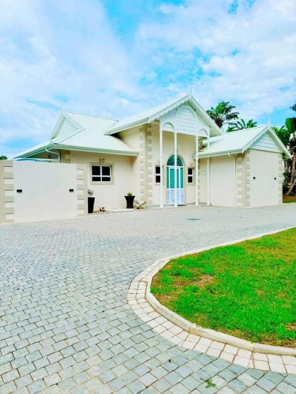 a white house with a driveway in front of it at Caribbean Estates Villa Varie - Luxury accommodation in Port Edward