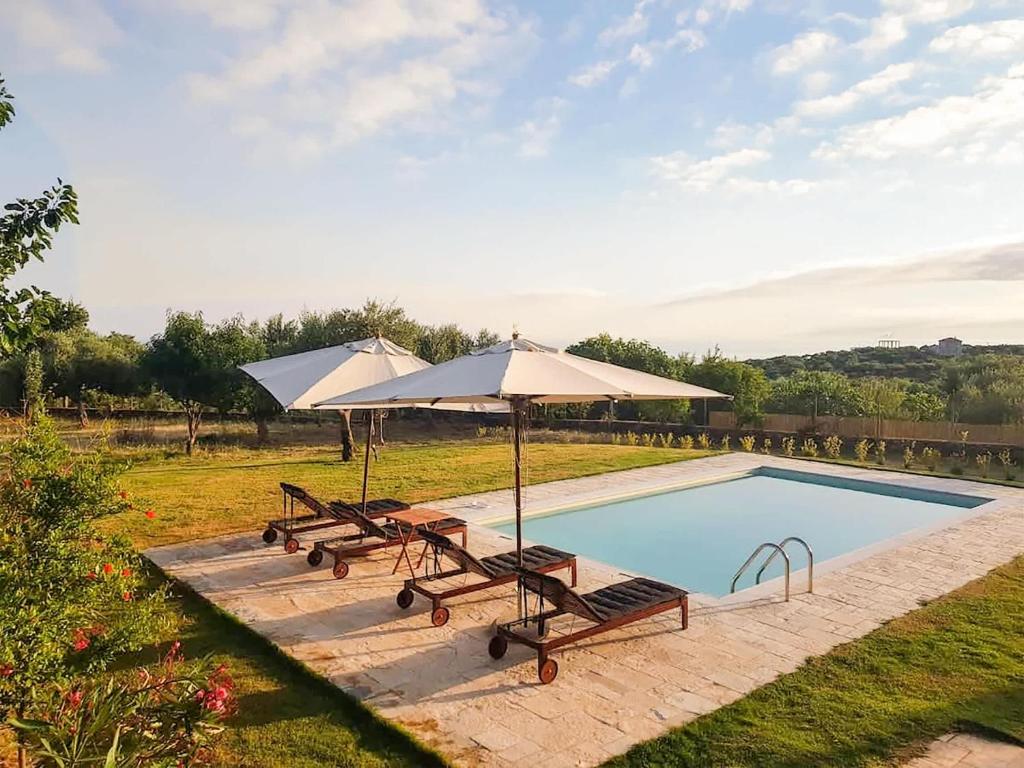 a swimming pool with two umbrellas and two chairs and a table at Villa Eleni - Private Pool Retreat near Kardamili in Proástion