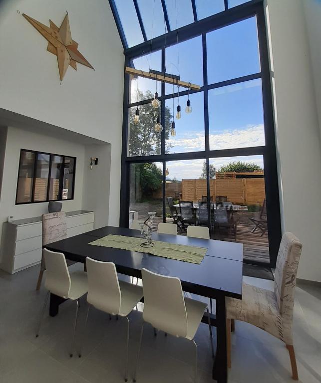 a dining room with a table and chairs and a large window at Gîte Ciel - 1-8 pers, au calme, à 20 mins du Puy-de-Dôme, Vulcania et le volcan de Lemptégy in Gelles
