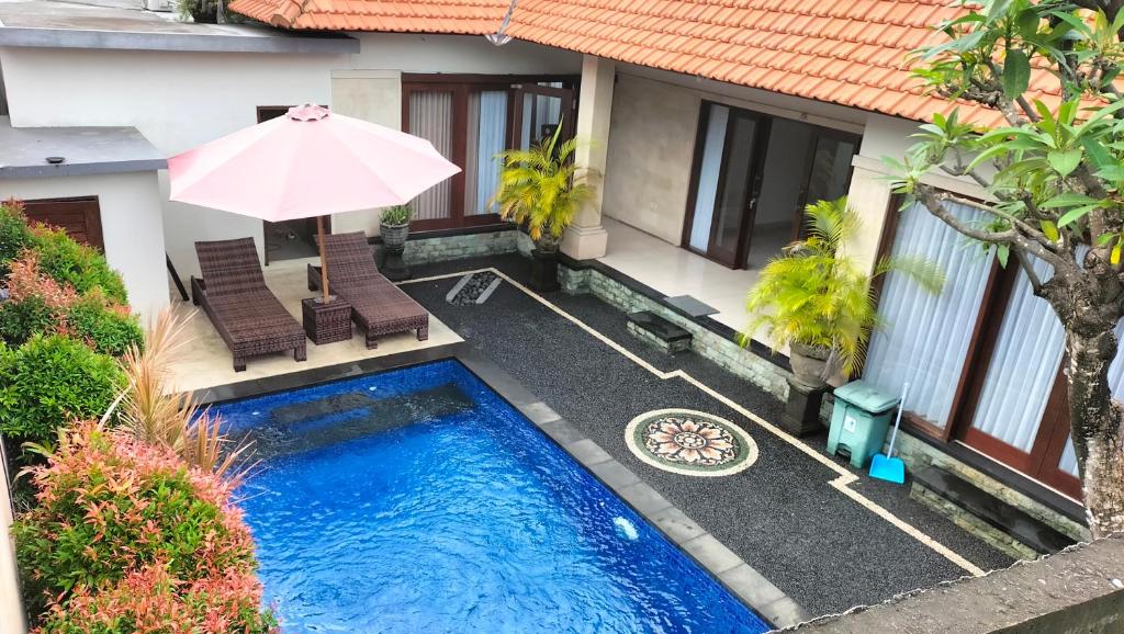 a swimming pool with two chairs and an umbrella at The Green Kamboja Villa in Sanur