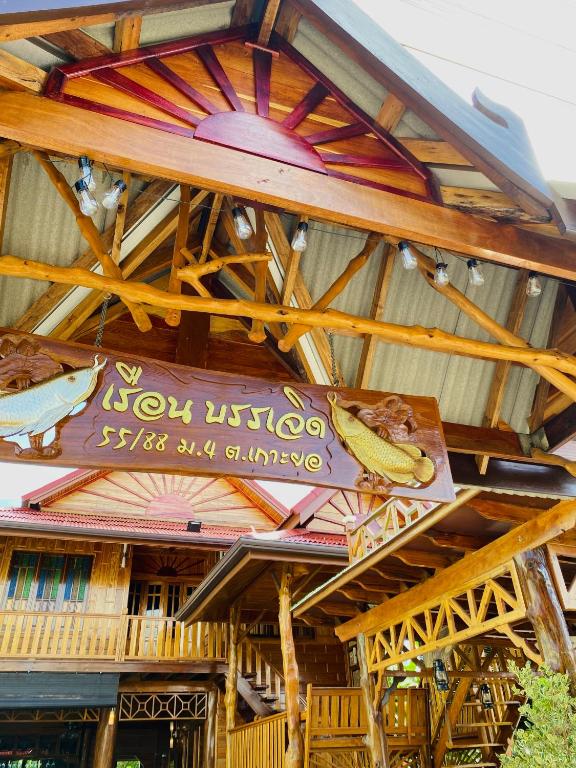 a building with a wooden roof with a sign on it at เรือนบรรเจิดโฮมสเตย์ in Ban Nok